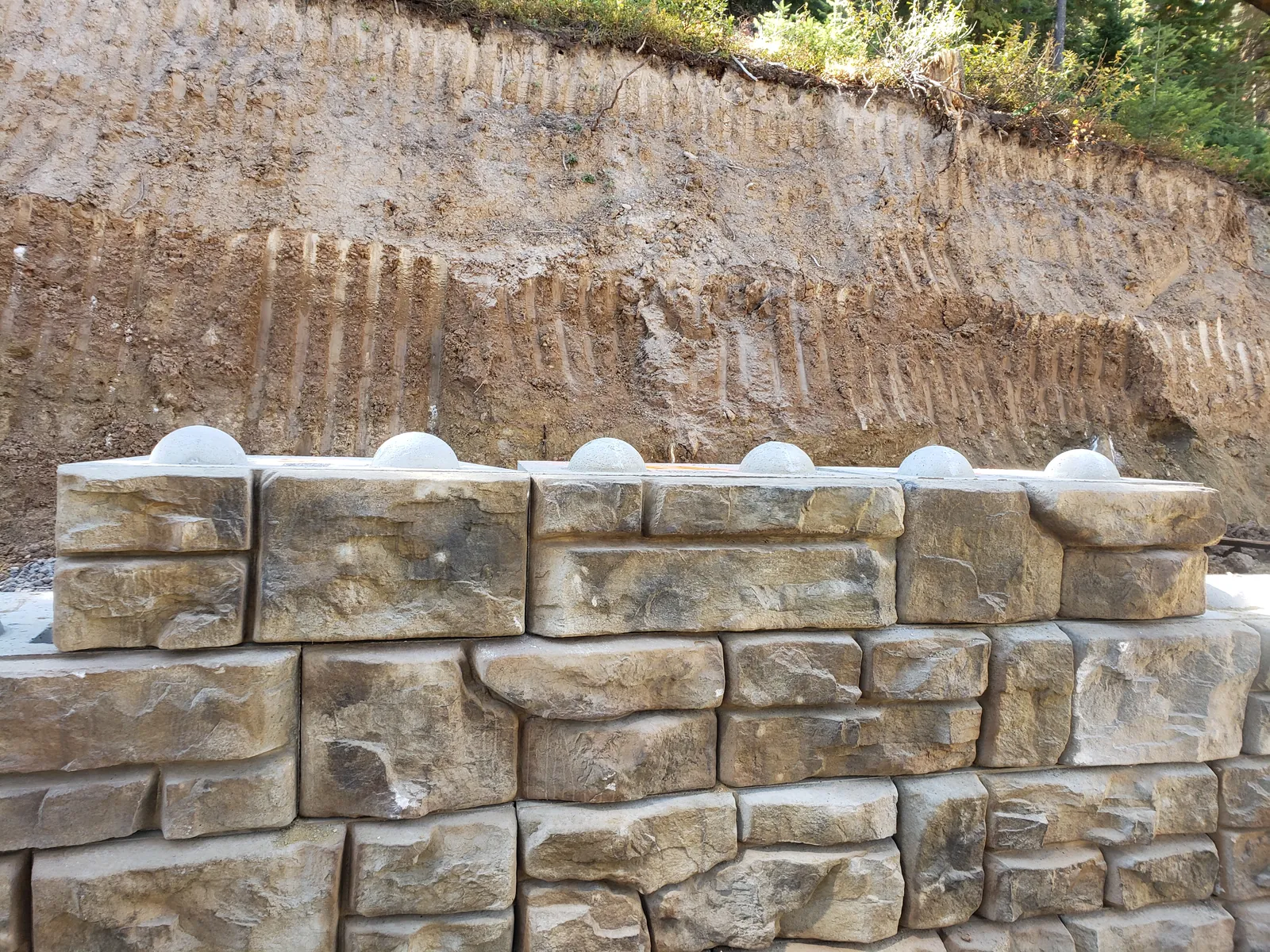 Large stone-faced retaining wall blocks against a cut bank
