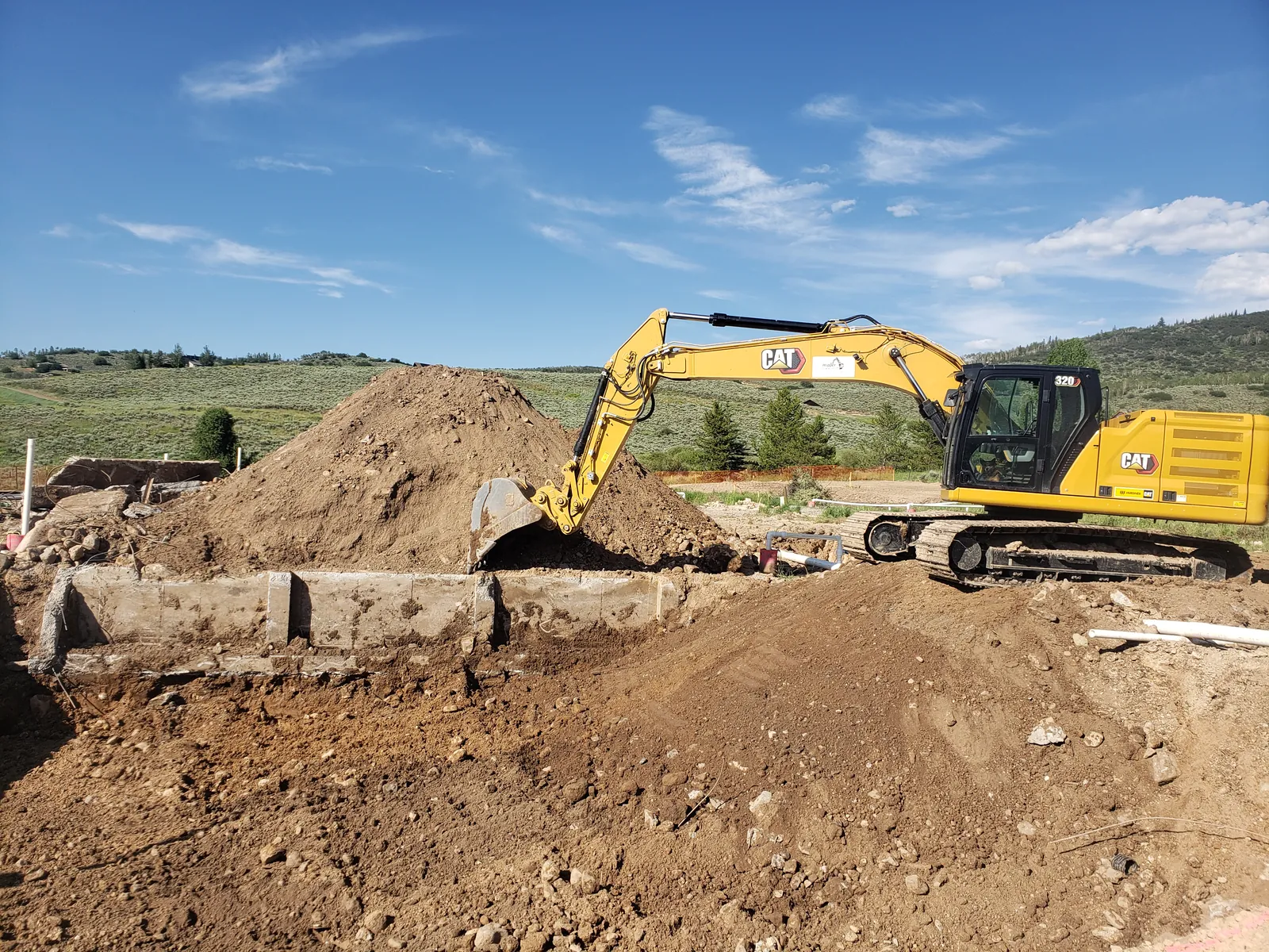 A CAT excavator loading a spoil pile on an open dig