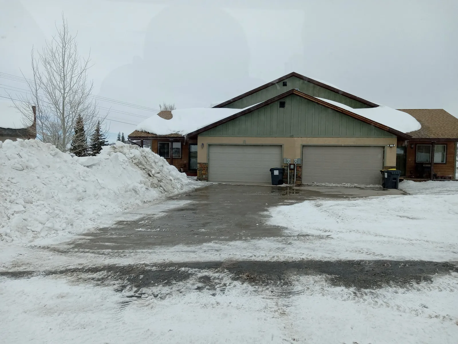 A cleared driveway in front of a duplex, snow banks piled high on the left