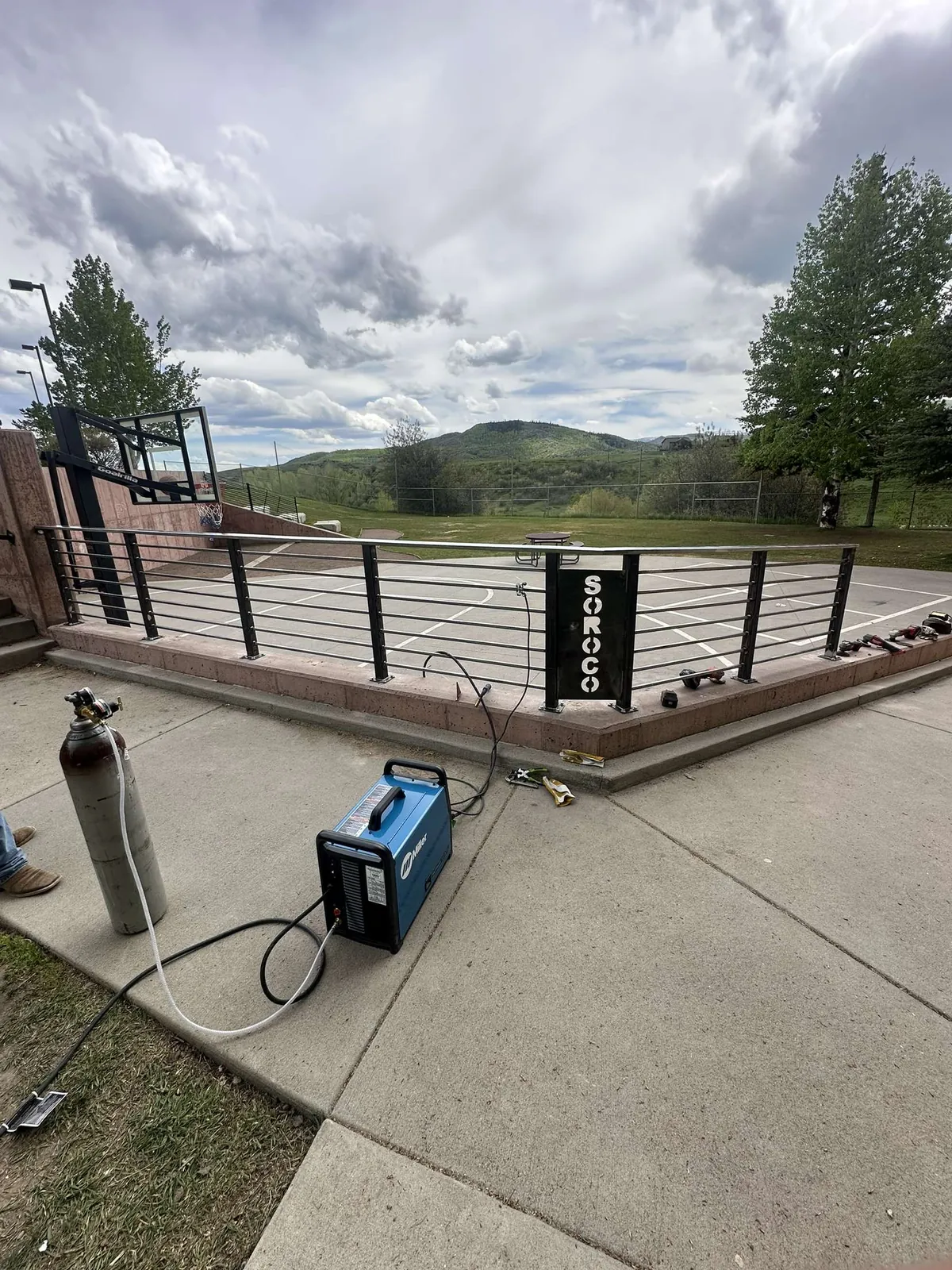 New steel cable railing with a SOROCO sign, a welder and gas bottle on the concrete